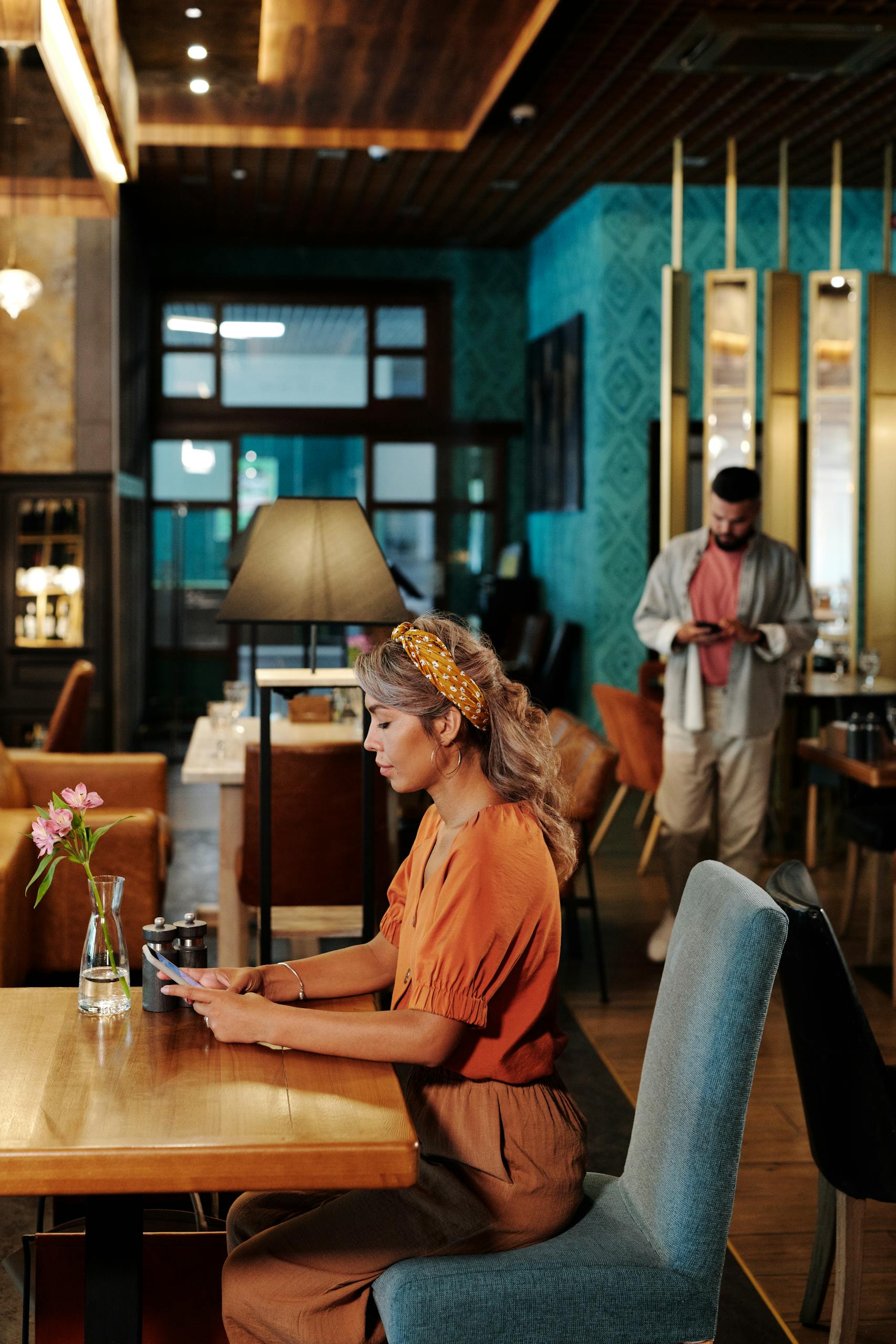 A woman and a man using their devices in a stylish, modern café setting.